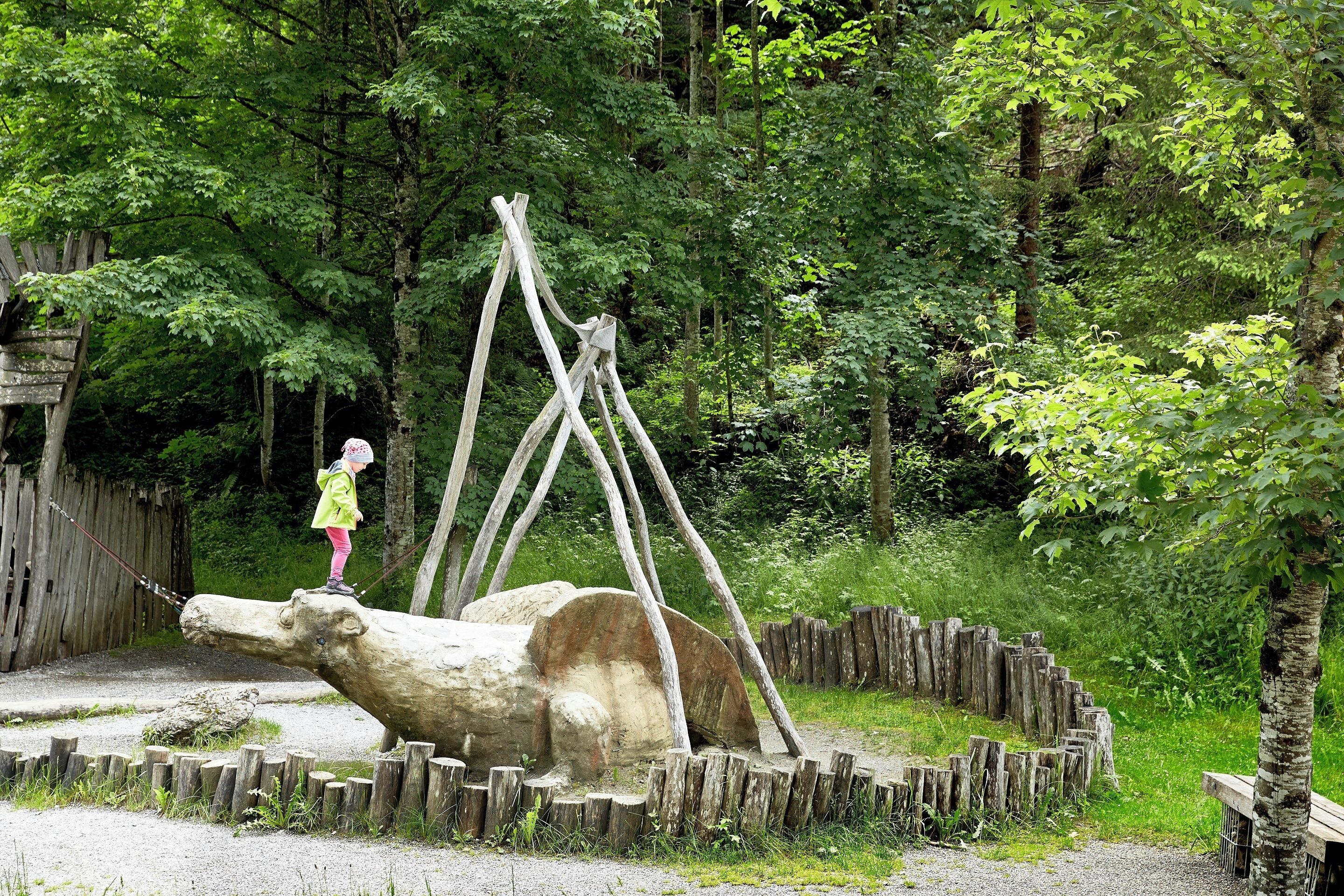 Eine Holzskulptur eines großen Tieres in einem bewaldeten Gebiet.