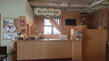 A reception area with a wooden counter, a sign reading "RECEPTION," and a staircase in the background.