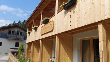 Un edificio de madera con balcones, un letrero que dice "DEPRENDANCE 2" y mobiliario exterior.