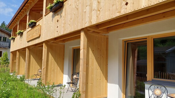 Un edificio de madera con balcones, mobiliario exterior y un jardín.