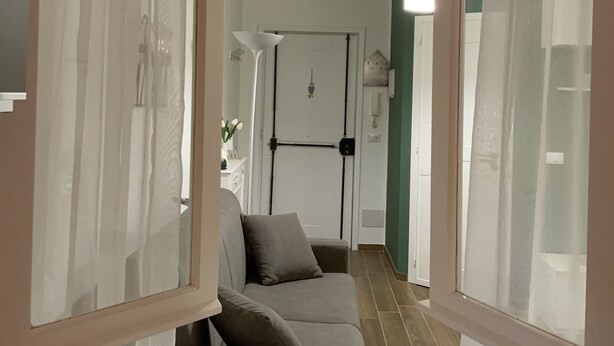 Een modern interieur met een bank, gordijnen en een gang naar een deur.