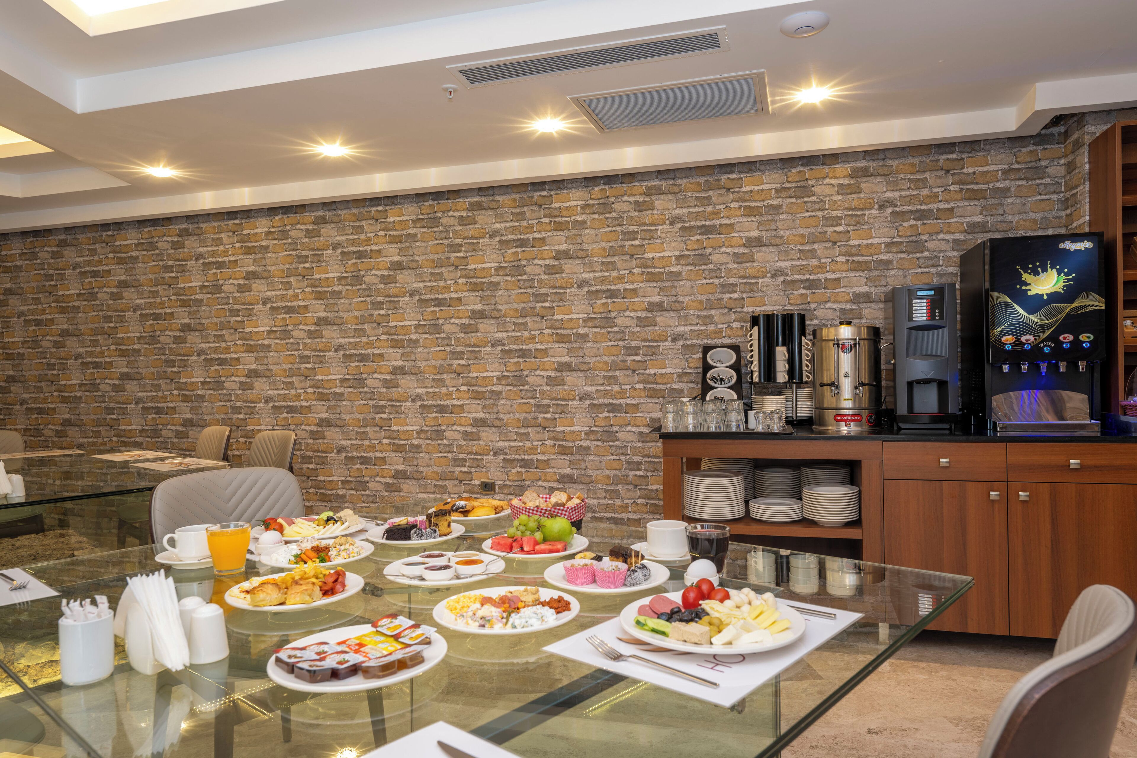 Un ricco buffet per la colazione con diversi piatti, una macchina per caffè e un dispenser di acqua.