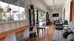 A modern interior with a wooden dining table, white chairs, a grey sofa, and a TV mounted on the wall. - Villela Stay - Villa Kubitschek - Country house Lago Sul Brasília-DF (Lago Sul)