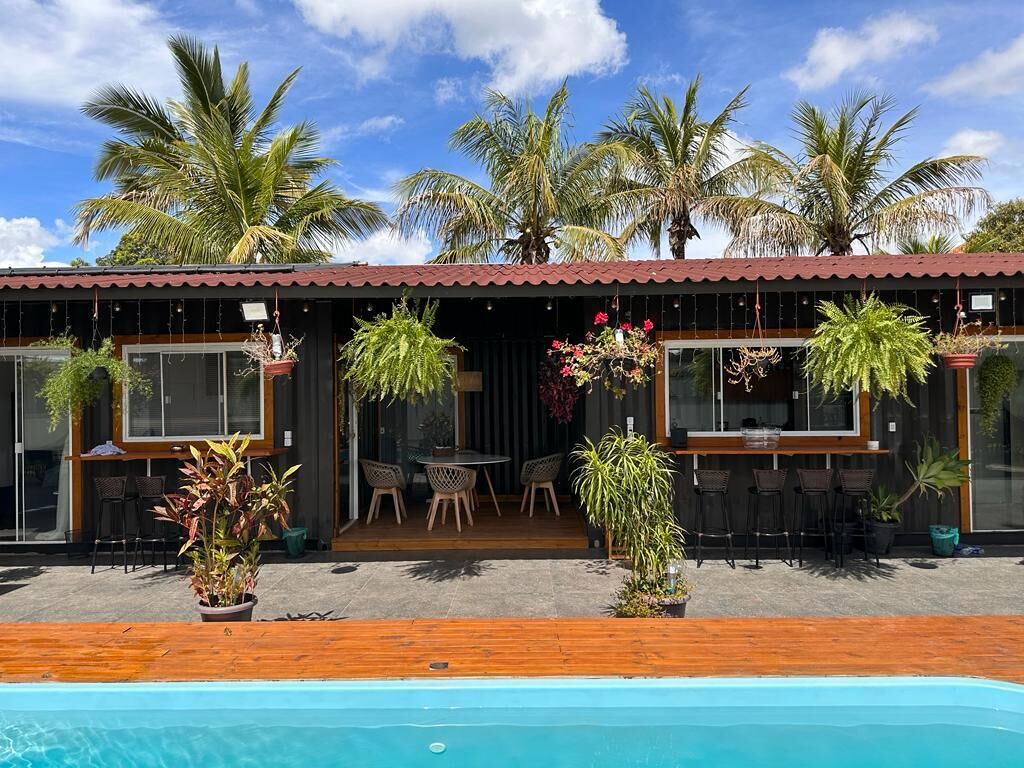 Ein Poolbereich mit Holzterrasse, Sitzgelegenheiten im Freien und Pflanzkübeln.