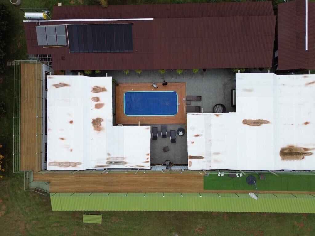 An aerial view of a building with a swimming pool, outdoor seating area, and a solar panel.