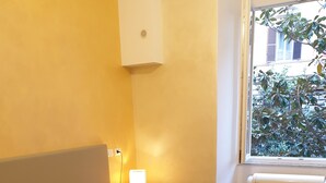 Ein Schlafzimmer mit Bett, Nachttischlampen, einem Fenster und einer Heizung.