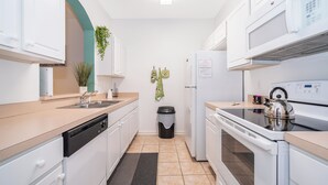 Une cuisine moderne avec des meubles blancs, un lave-vaisselle, une cuisinière et un four à micro-ondes.