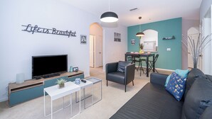 Un salon moderne doté d’un téléviseur à écran plat, d’un canapé, d’une table basse et d’un coin repas avec une table et des chaises.