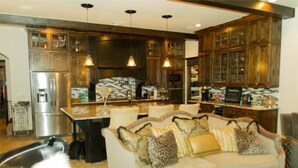 A modern kitchen with dark wood cabinets, stainless steel appliances, and pendant lighting.