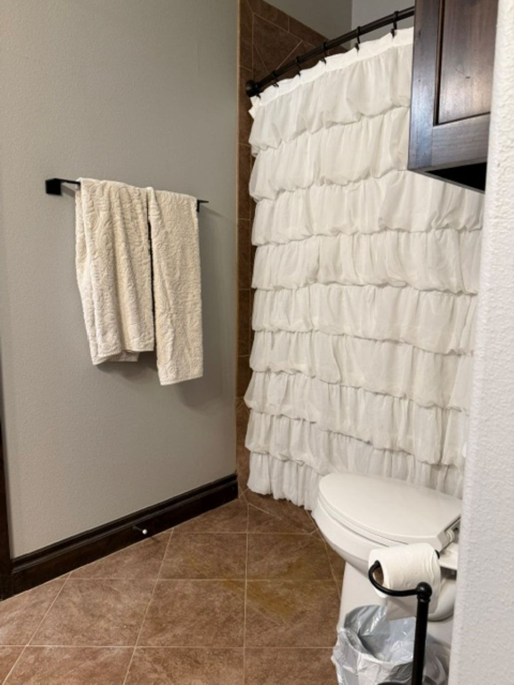 Une salle de bain équipée de toilettes, d’un rideau de douche et d’un porte-serviettes avec deux serviettes.
