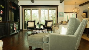 A spacious living room with a large window, a ceiling fan, and a fireplace.