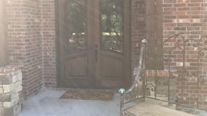 A brick entrance with a wooden door and a metal bench.