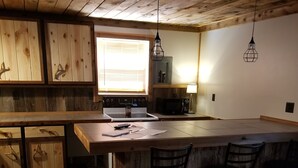 Una cocina con armarios de madera, estufa, microondas y una barra con taburetes.
