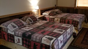 Una habitación con dos camas, cada una cubierta con un edredón estampado, una mesita de noche con lámpara y una ventana con persianas.