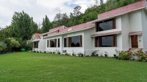 A two-story white building with large windows and a red roof, surrounded by a well-maintained lawn and trees. - Orania by Atsar (Srinagar)