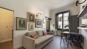 A living room with a sofa, a dining table, and a chandelier. - Ognissanti Flat by Mmega (Florence)