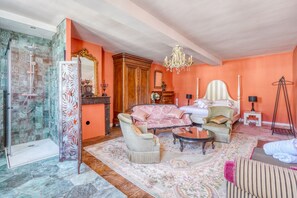 A room with a shower, a sofa, a chair, a bed, and a chandelier. - Le Castel de Castillon - Maison d'exception à 10 minutes de Saint Emilion (Castillon-la-Bataille)