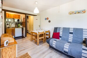 Un espacio habitable compacto con kitchenette, comedor y sofá.