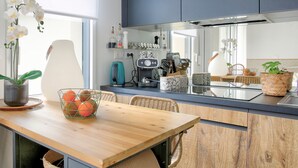 Eine moderne Küche mit einem Holztisch, Korbstühlen und verschiedenen Küchengeräten und Utensilien.