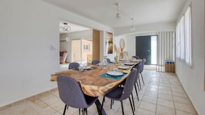 Un espace repas avec une longue table en bois, dressée pour six personnes, entourée de chaises.