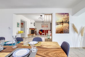 Uma sala de jantar com mesa de madeira posta para quatro pessoas, lareira e vista para a cidade através de uma janela.