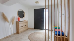 Une chambre à coucher avec un lit, une commode en bois, un miroir et une porte.