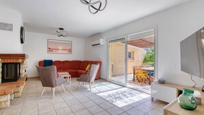 Un salon spacieux avec une cheminée, un grand canapé et un téléviseur.