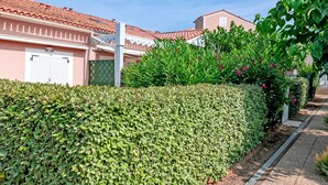 A neatly trimmed hedge, a building with a red-tiled roof, and a clear blue sky. - Le Scarlett - Maison à 300m de la plage (Palavas-les-Flots)
