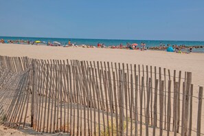 A beach with a wooden fence in the foreground.