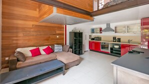 A modern kitchen with red cabinets, a built-in oven, and a coffee machine. - Le Scarlett - Maison à 300m de la plage (Palavas-les-Flots)