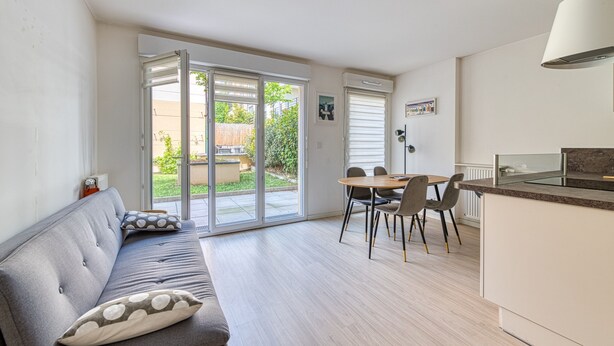 Een moderne keuken met een eethoek, een bank met kussens en een schuifpui naar een terras.