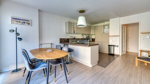 Een moderne keuken met een centraal eiland, een eethoek met een ronde tafel en stoelen, en een gang die naar een andere kamer leidt.