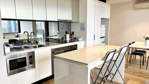 Una cocina moderna con armarios blancos, electrodomésticos de acero inoxidable y una isla central con taburetes de bar.