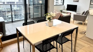 Un apartamento moderno con comedor, sala de estar y un amplio ventanal con vista a la ciudad.