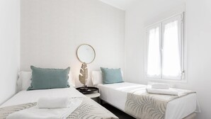 Ein modernes Schlafzimmer mit zwei Einzelbetten, einem runden Spiegel und einem kleinen Nachttisch.