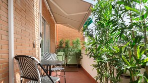 Eine kleine Außenpatio mit Backsteinmauer, einem Tisch, zwei Stühlen und Blumentöpfen.
