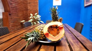 Uma mesa de madeira com uma abacaxi e meia papaia.