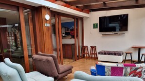 Uma sala de estar moderna com assentos confortáveis, uma TV de tela plana e teto de madeira.