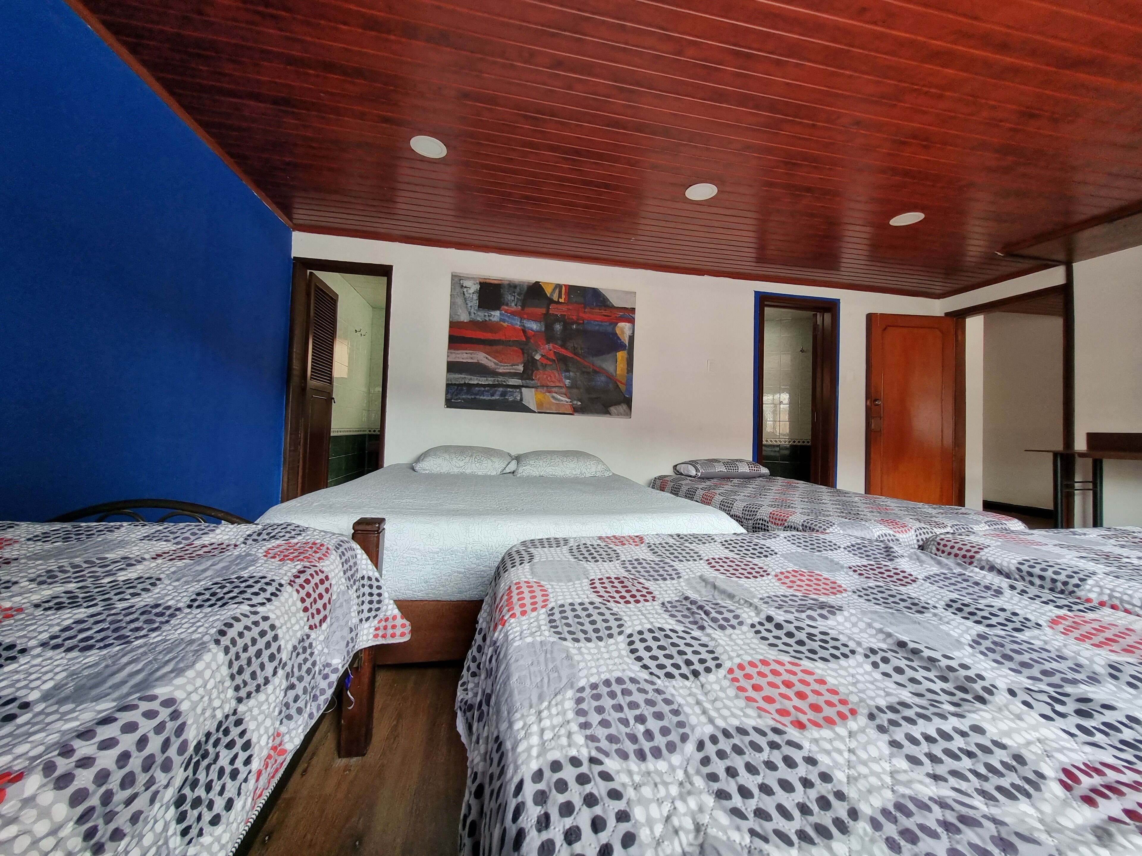 Une chambre d’hôtel avec deux lits, un plafond en bois et un tableau au mur.