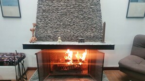 Uma lareira moderna com fachada de pedra, um parapeito com objetos decorativos e frente de vidro transparente.