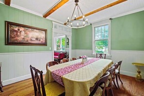 Una sala da pranzo con un lungo tavolo, sedie, un lampadario e un quadro appeso al muro.