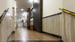 Un pasillo moderno de hotel con paredes de mármol, escalones de madera y una barandilla.