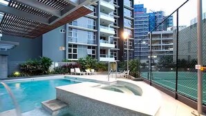 Un bâtiment moderne doté d’une piscine, d’un espace extérieur aménagé et d’un court de tennis.