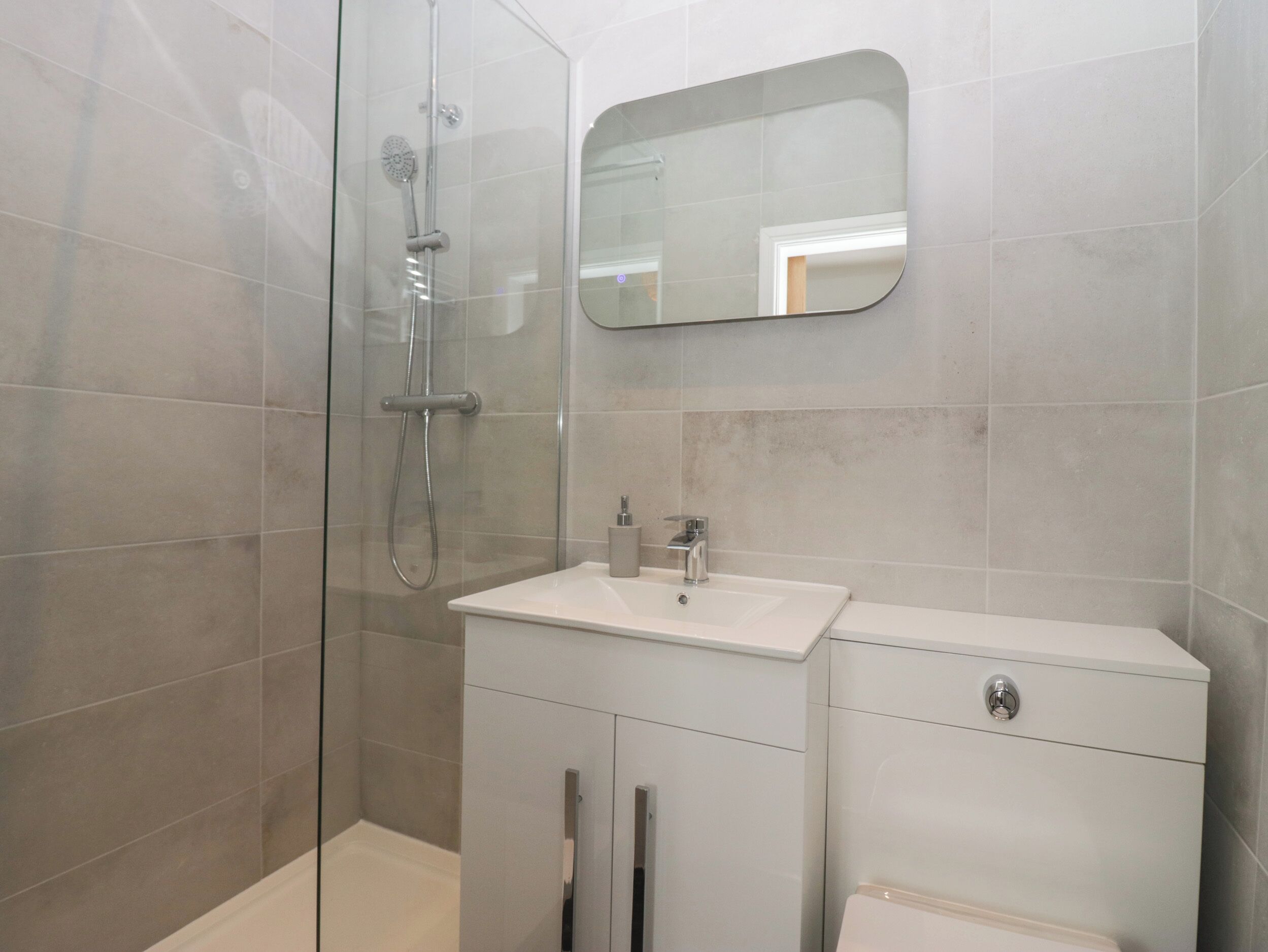Une salle de bain moderne avec une douche à parois de verre, un lavabo blanc et des toilettes.