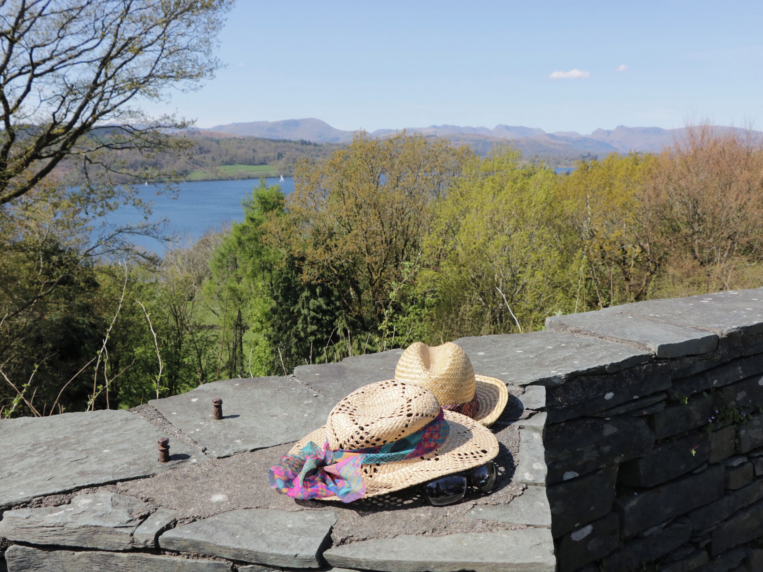 A stone wall with a straw hat and sunglasses placed on it.