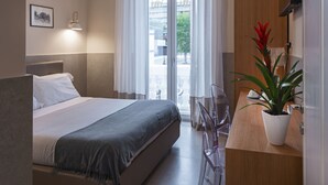 Una habitación de hotel moderna con cama, escritorio, silla, planta en maceta y vistas al exterior.
