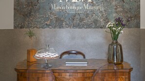 Un mostrador de recepción con pared de mármol, un jarrón con flores y un pastel sobre un pedestal de vidrio.