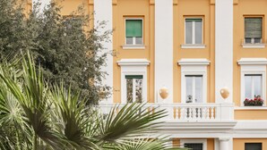 Un edificio con fachada amarilla, contraventanas verdes y balcones blancos.