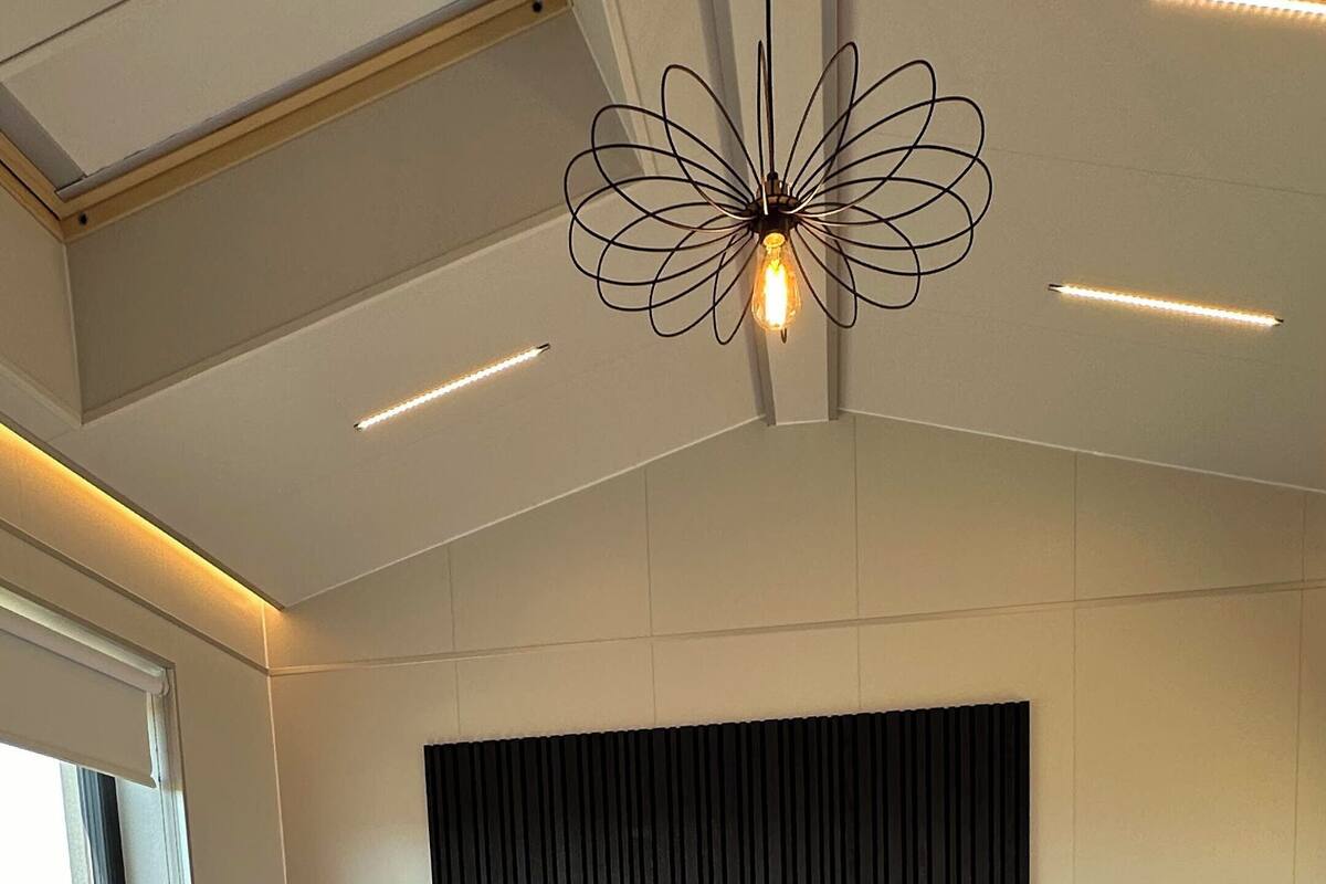 A modern bedroom with a large bed, two bedside tables, a dark headboard, and a unique ceiling light fixture.