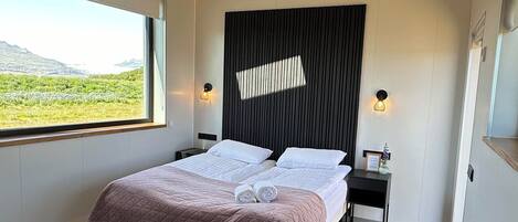 Un dormitorio moderno con una cama grande, tragaluces, suelo de madera y una mesita.